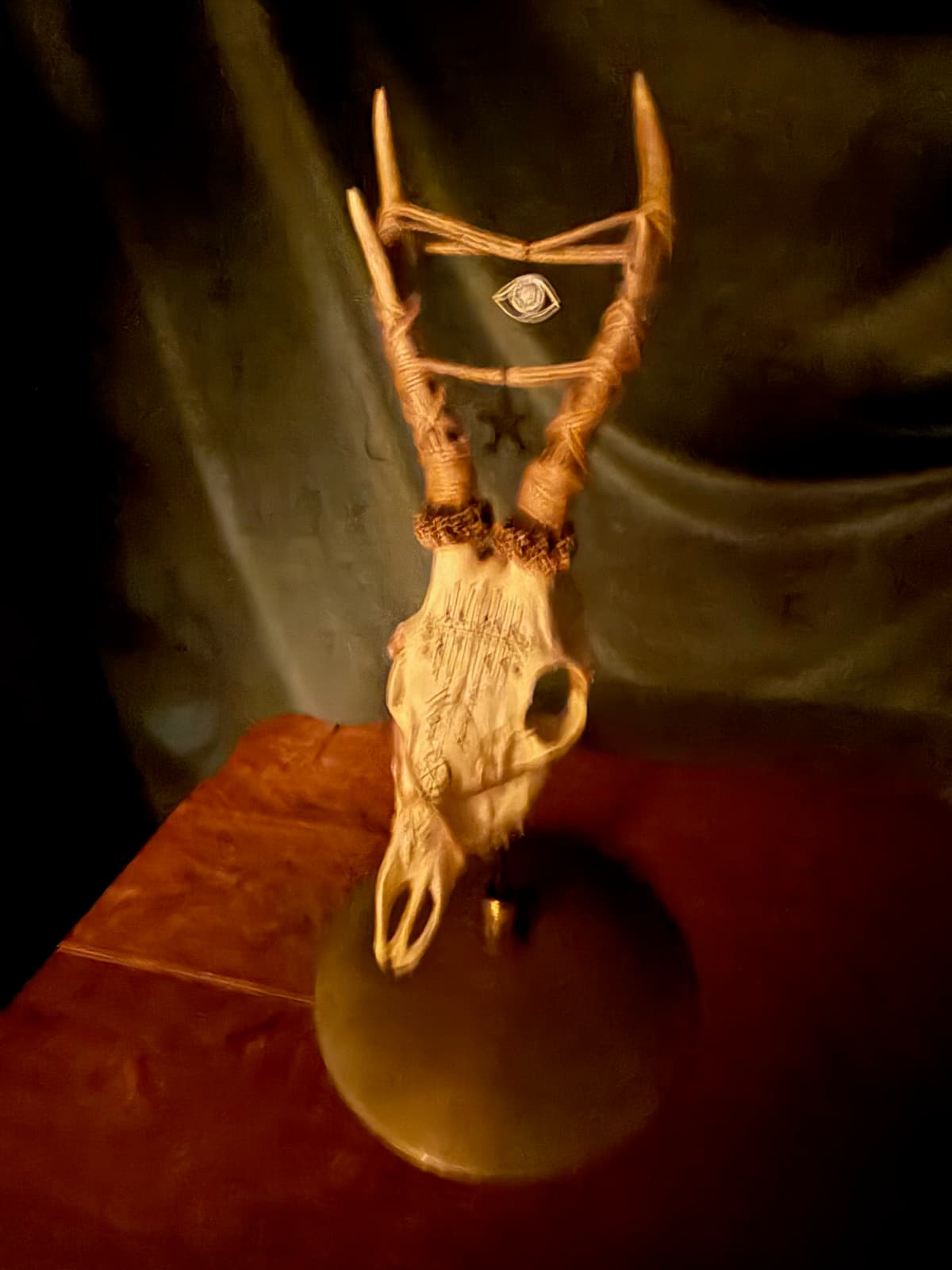 A carved deer skull with an eye charm strung between its antlers.